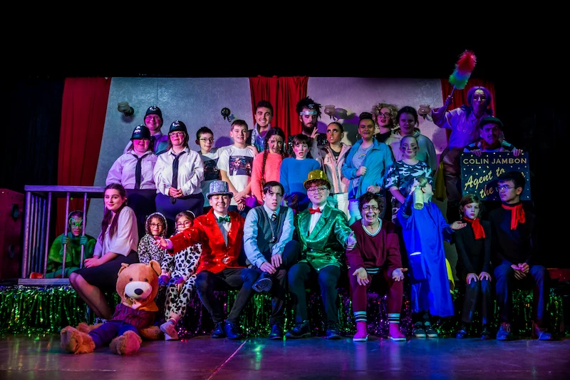 Group photo of 25 actors in costume including a bear, fish and policeman.