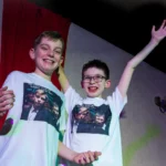 Two child actors. One with hands in the air