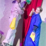 Actress and child actor dusting curtains