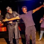 4 Actors together. Actor in the middle has arms out