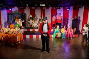 Ensemble of actors dressed as carnval performers