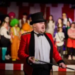 Actor dressed as ring master infront of ensemble
