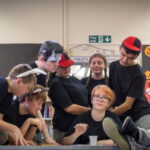 Ensemble of actors dressed as story book character around table