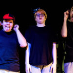 Three actors standing in a line with bird hats