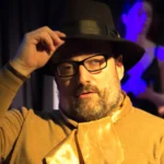 Actor with wide brimmed hat looking into distance