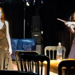 Two actresses. one pointing prop gun