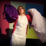 Actress holding a wedding dress and purple dress