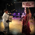 Actor standing opposite each other. one of the actors throwing corn