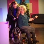 Actor pushing other actor in wheelchair