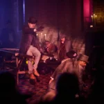 Actor on table pointng at audience