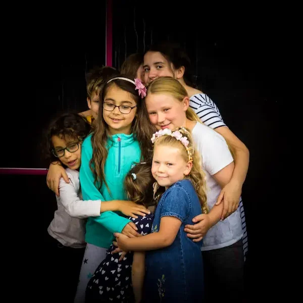 Eight children hugging for a photo.