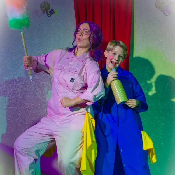 An adult and child actor dressed in colourful cleaning clothes doing a funny pose.