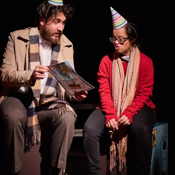 Two actors dressed in party hats.