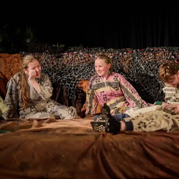 Three young actors dressed in overalls with snakeskin patterns in a show called The Snake Pit.