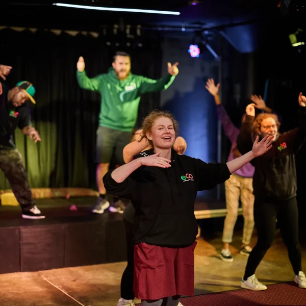 A young woman rehearsing on stage with her hand on her chest, singing.