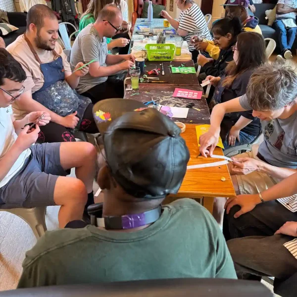 Ten EGO artists hard at work creating art around a long table.