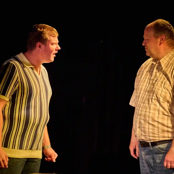 An actor confronts another menacingly in a scene from a show.