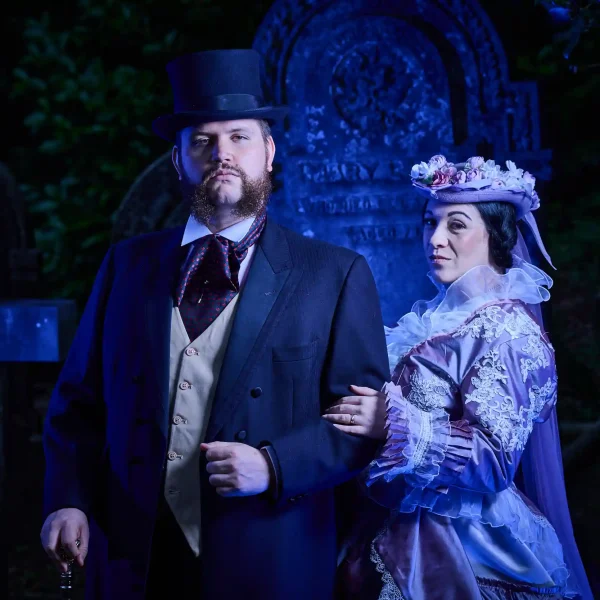 A man and woman in Victorian clothing in a cemetery.