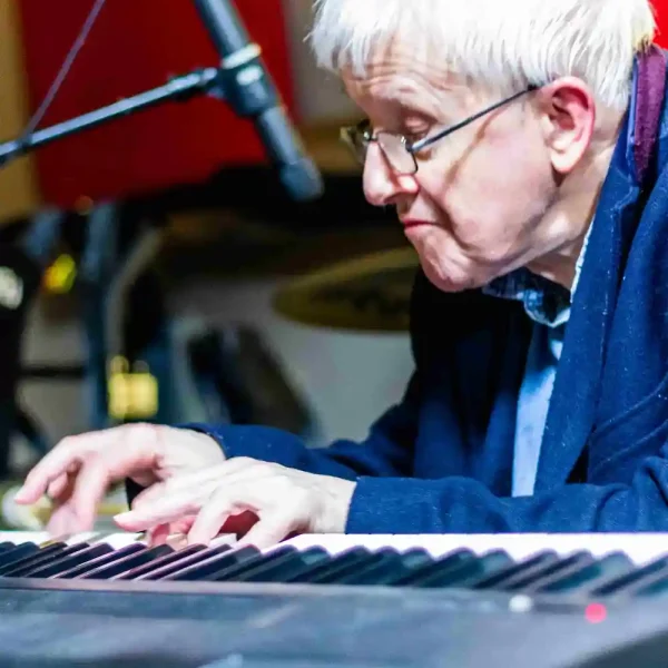 A gentleman playing the keyboard in a music studio.