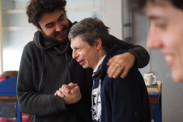 Two men shake hands, one with his arm around the other.