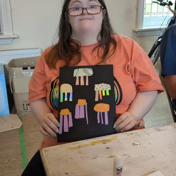 An EGO artist holds up a jellyfish artwork she has made by layering different bits of paper with glue.